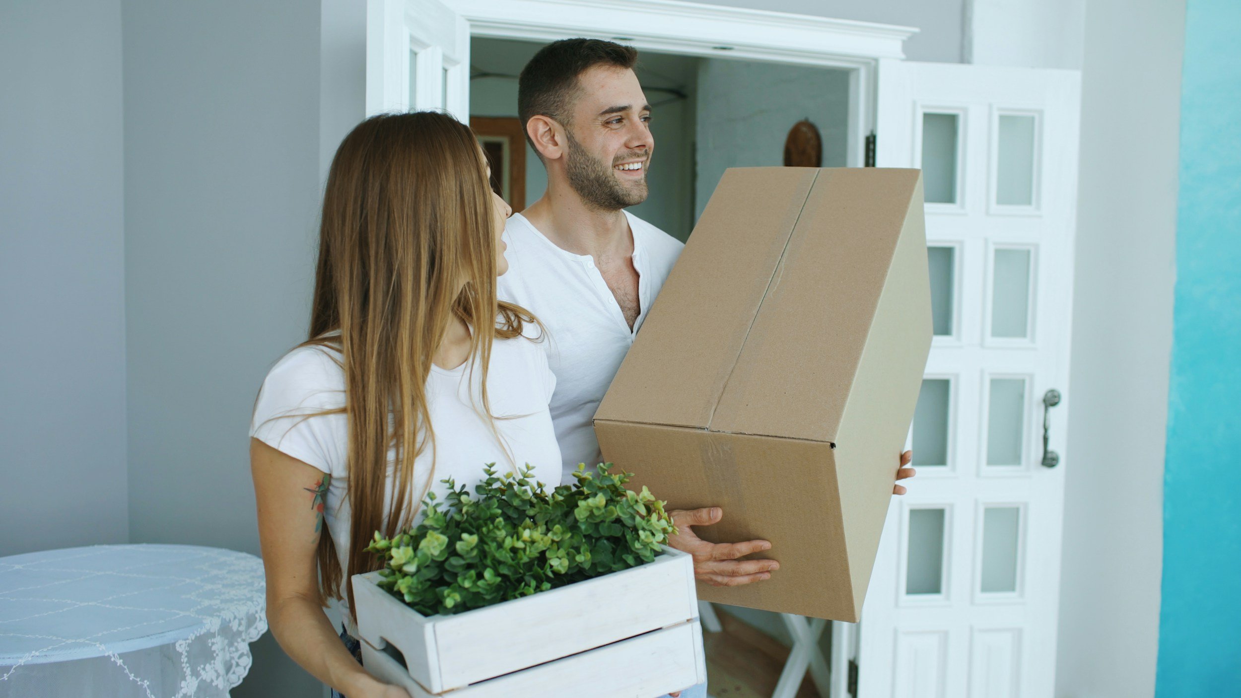 Couple carrying boxes into a new home